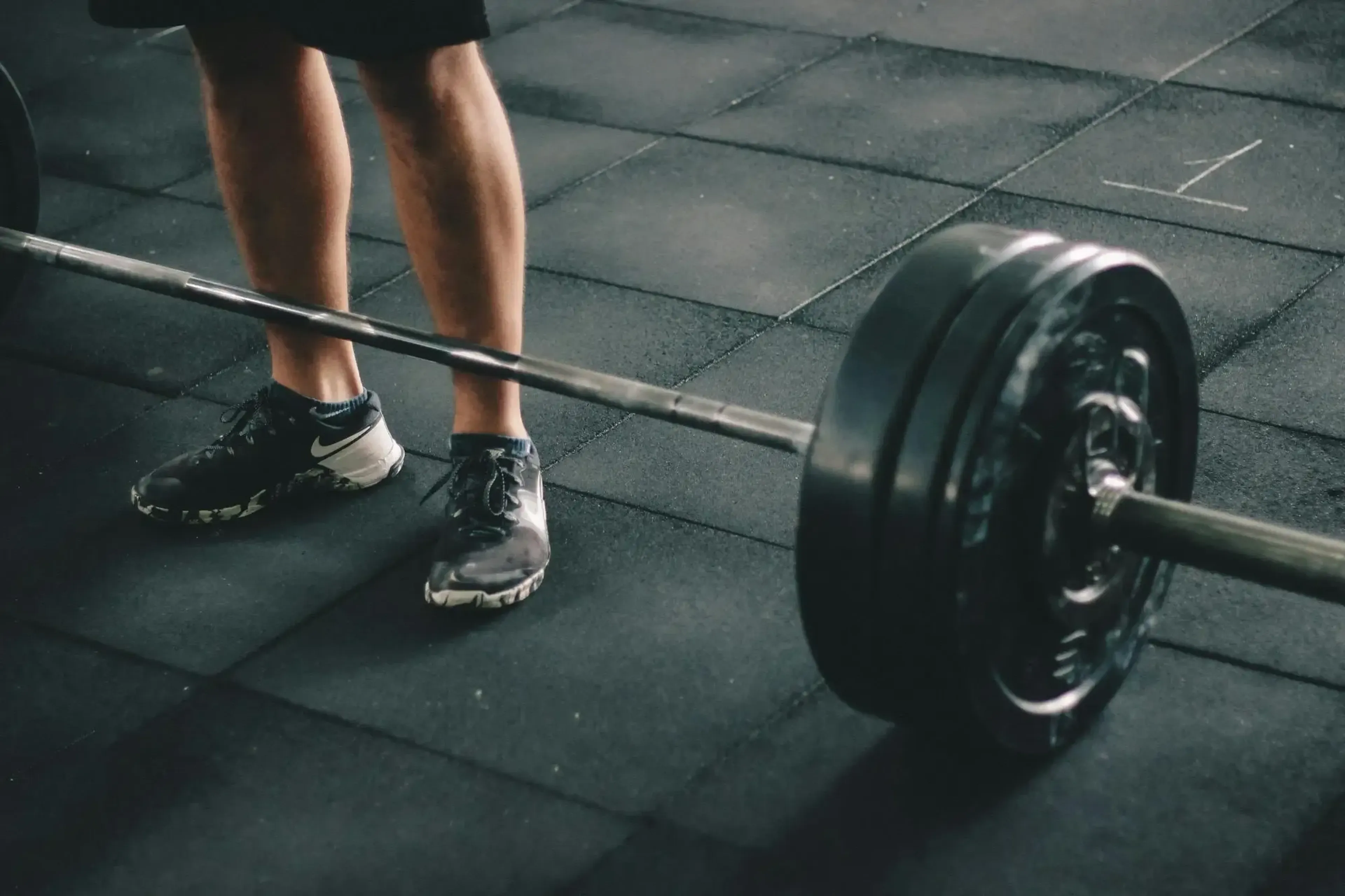 Loaded barbell on a floor with a person standing behind it